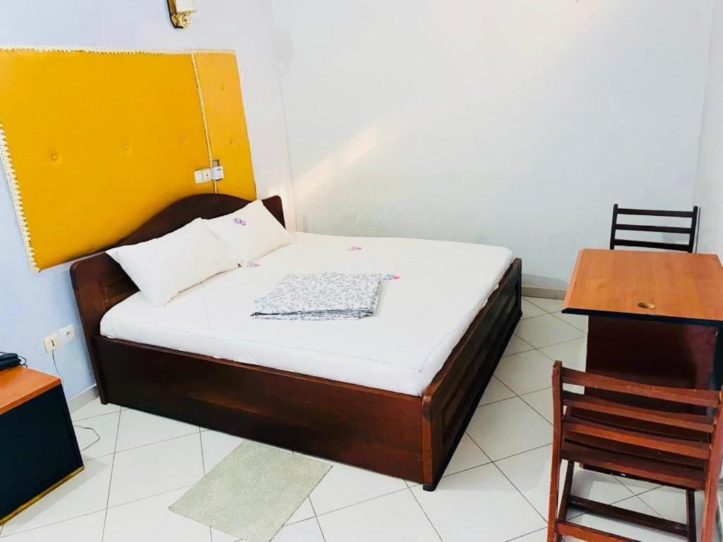 Cama en habitación con mesa y silla en AULNES RESIDENCE HOTEL, en Cotonou