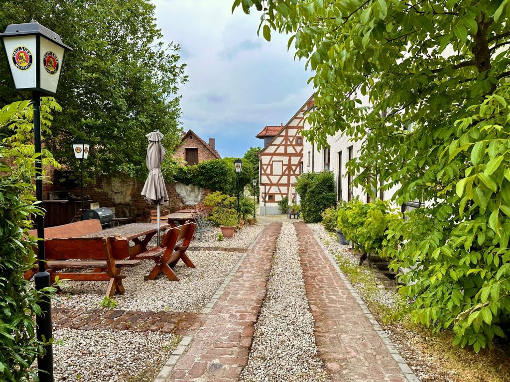 a garden with a bench and a table and an umbrella at Hotel Kastanienbaum in Herzogenaurach