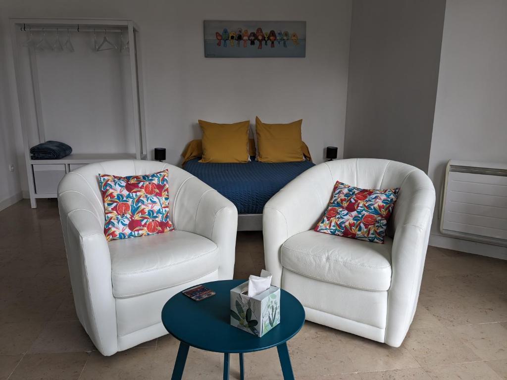 een woonkamer met 2 stoelen en een tafel bij Les Jolis Nids - Studio Rouge Gorge in La Roche-Posay