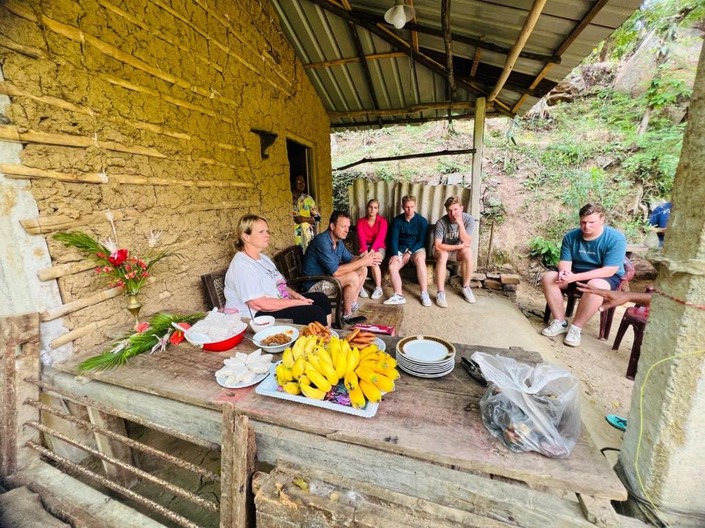 Samson Mud House في Mawanella: مجموعة من الناس يجلسون على طاولة مع الموز