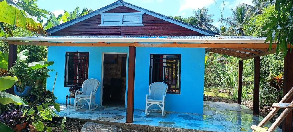 ein kleines blaues Haus mit zwei Stühlen davor in der Unterkunft Casa de campo in San Felipe de Puerto Plata