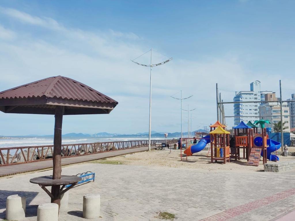 a playground on the beach with an umbrella at FrenteMar OuroVerde BetoCarrero in Navegantes