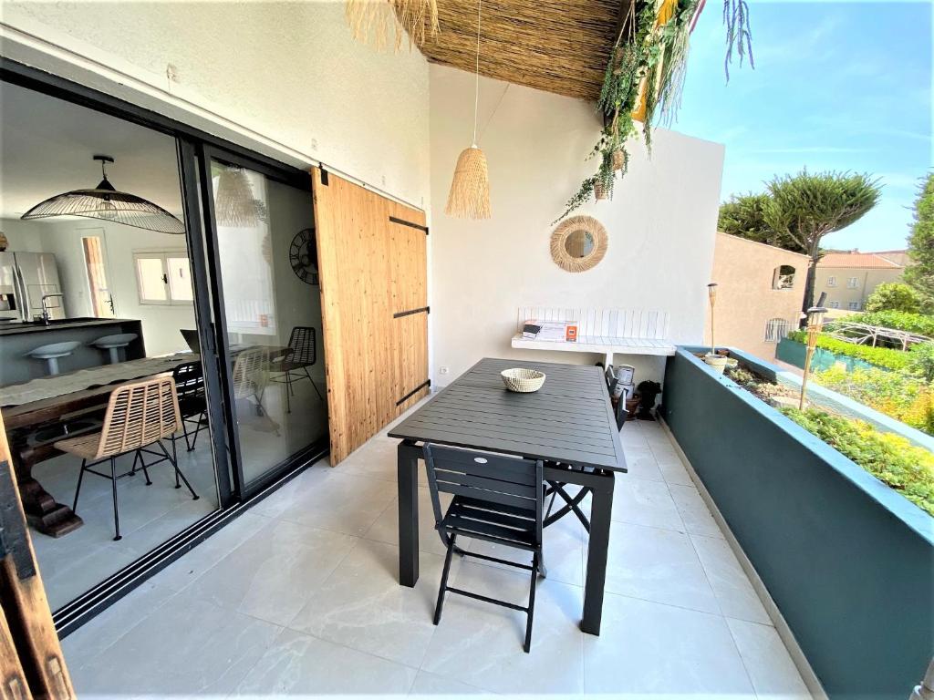 une petite table noire sur un patio avec une cuisine dans l'établissement Le Cosy Beach, à Saint-Cyr-sur-Mer