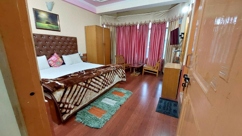 a bedroom with a large bed and a wooden floor at Hotel Jubilant Manali in Manāli