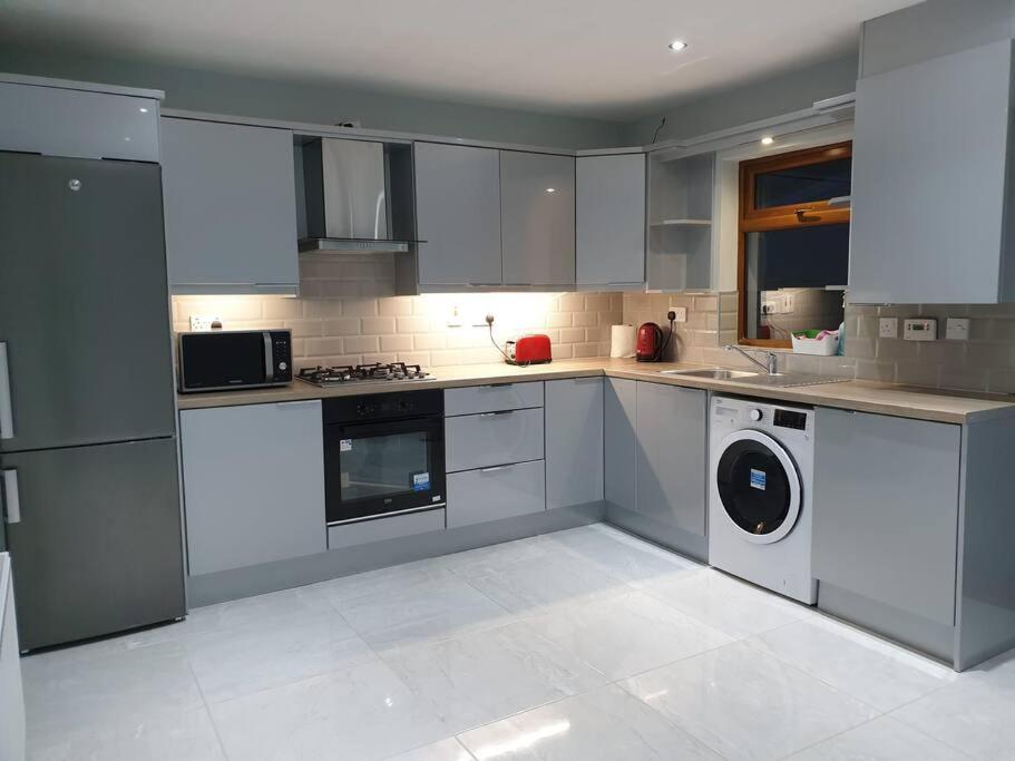 cocina con armarios blancos, lavadora y secadora en Cozy Studio Apartment, en Dublín