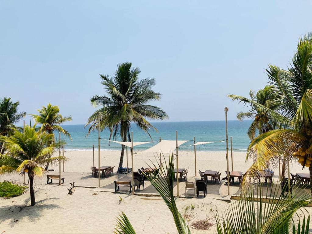 a beach with tables and chairs and the ocean at Honduras Shores Plantations in Tela