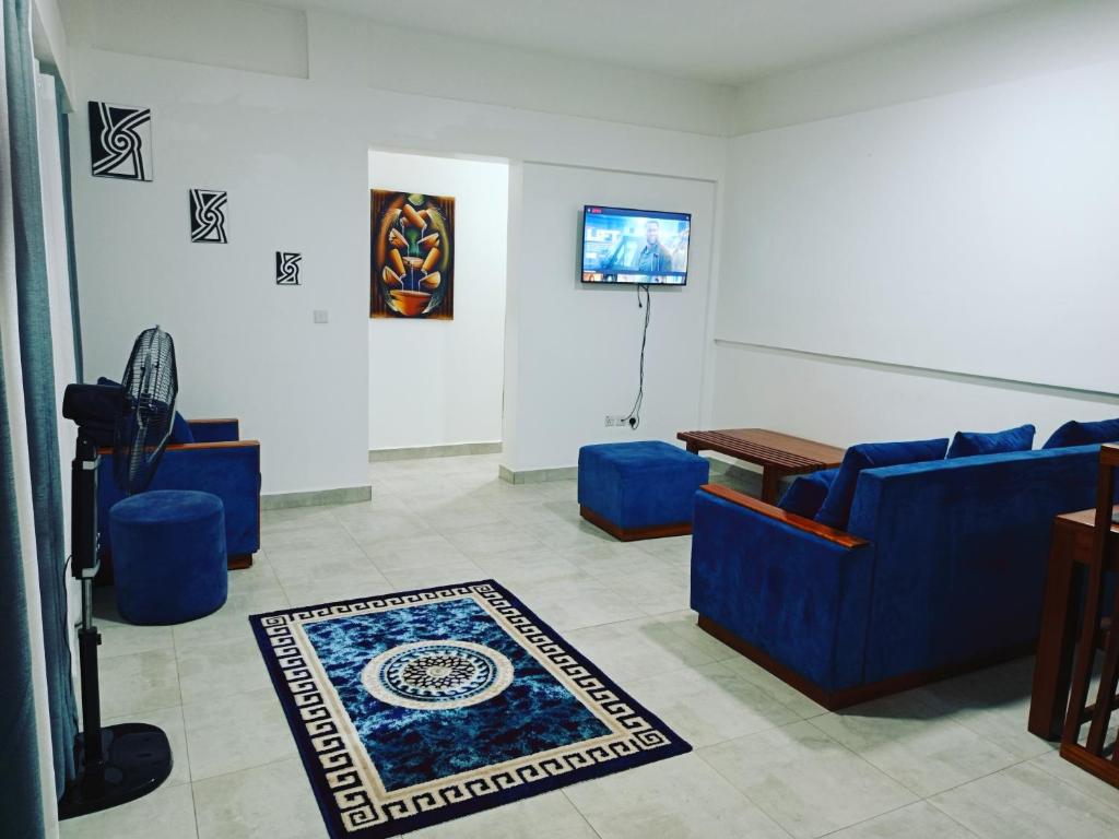 ein Wohnzimmer mit 2 blauen Sofas und einem TV in der Unterkunft Simon's Place in Kigali