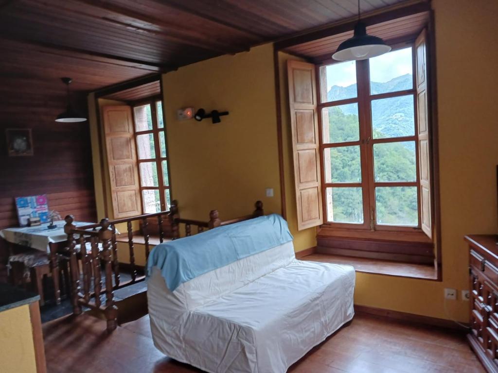 a bedroom with a bed and a table and windows at OSO4 in Pola de Somiedo