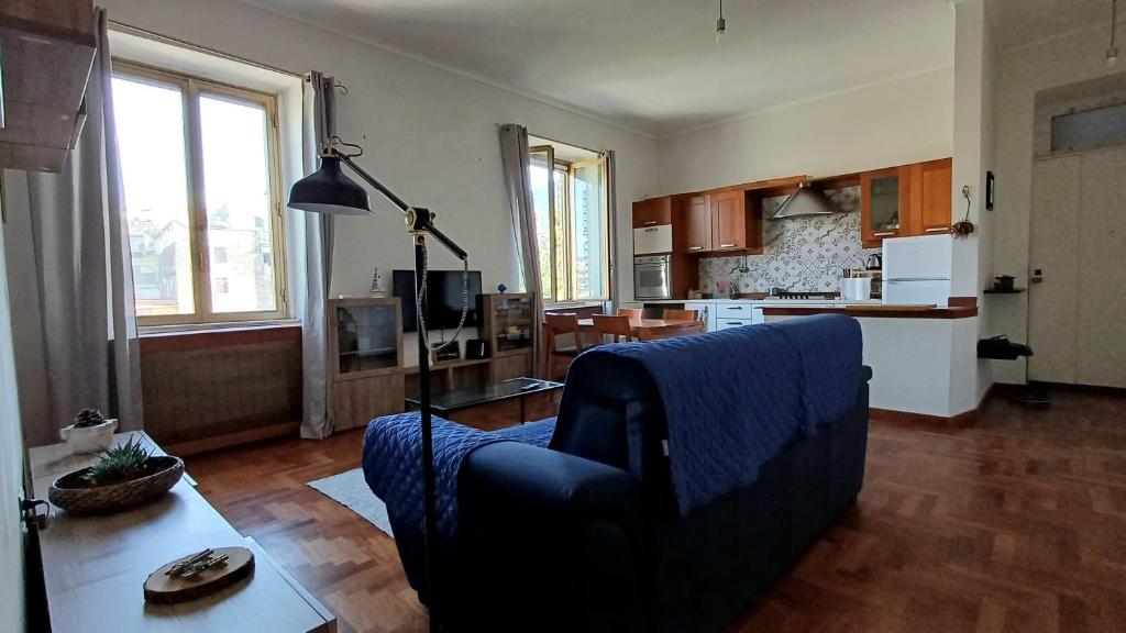 a living room with a blue couch and a kitchen at Appartamento La Vecchia Ferrovia in Castellammare di Stabia