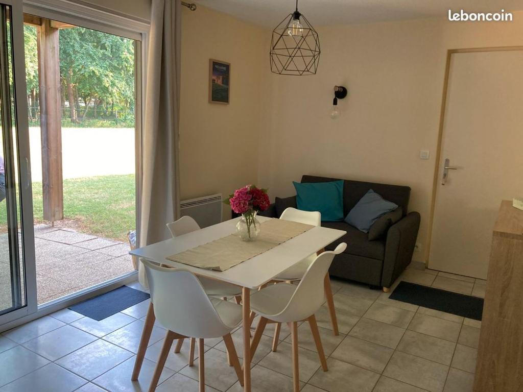 een woonkamer met een tafel en stoelen en een bank bij Vacances ou CNPE - Appart 2-3 pers - le Relais du Plessis - RICHELIEU in Chaveignes
