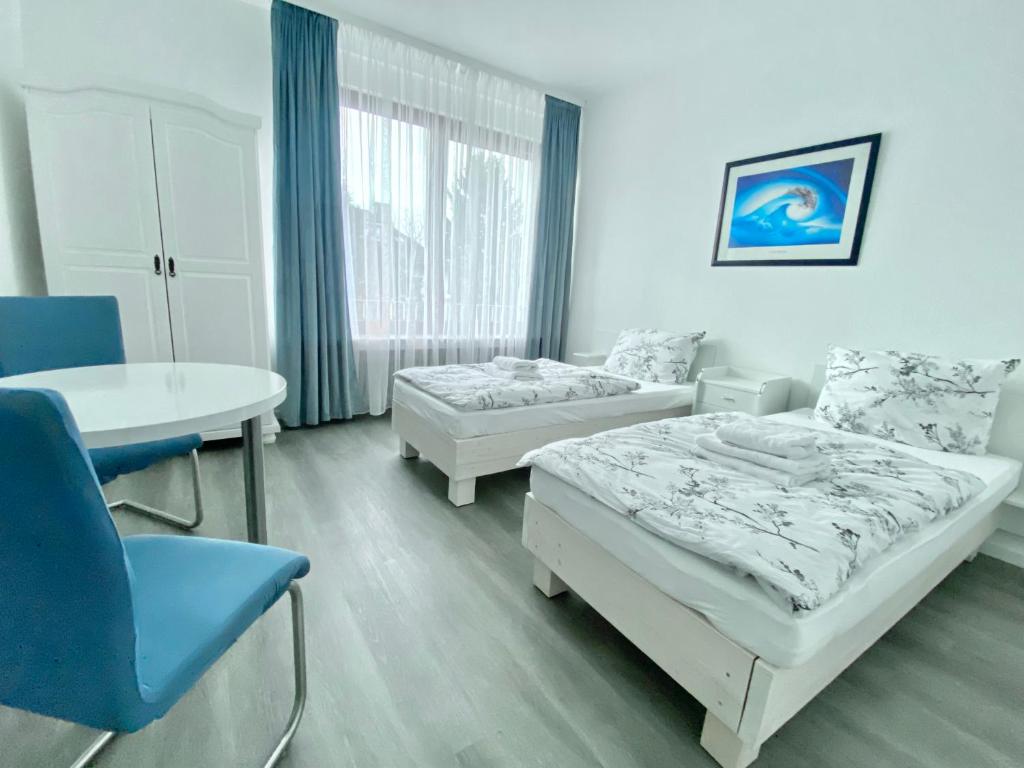 a room with two beds and a table and a table and chair at Stay Westend in Wetzlar