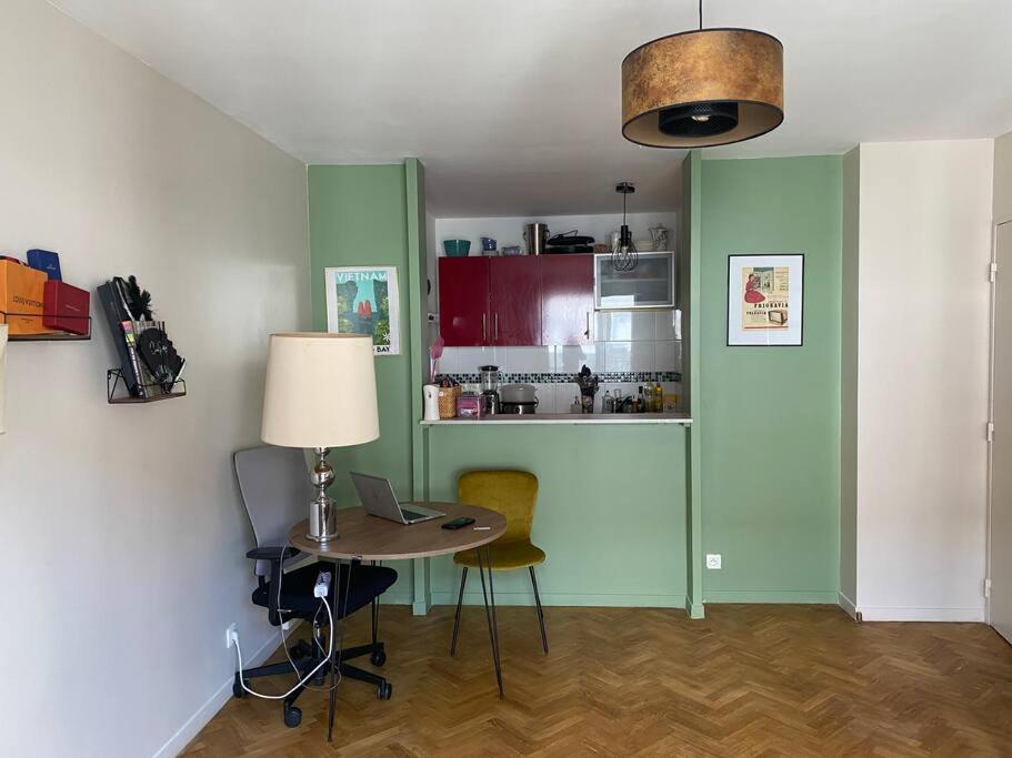 une chambre avec une table et un ordinateur portable ainsi qu'une cuisine dans l'établissement Appartement Stade de France, à Saint-Denis