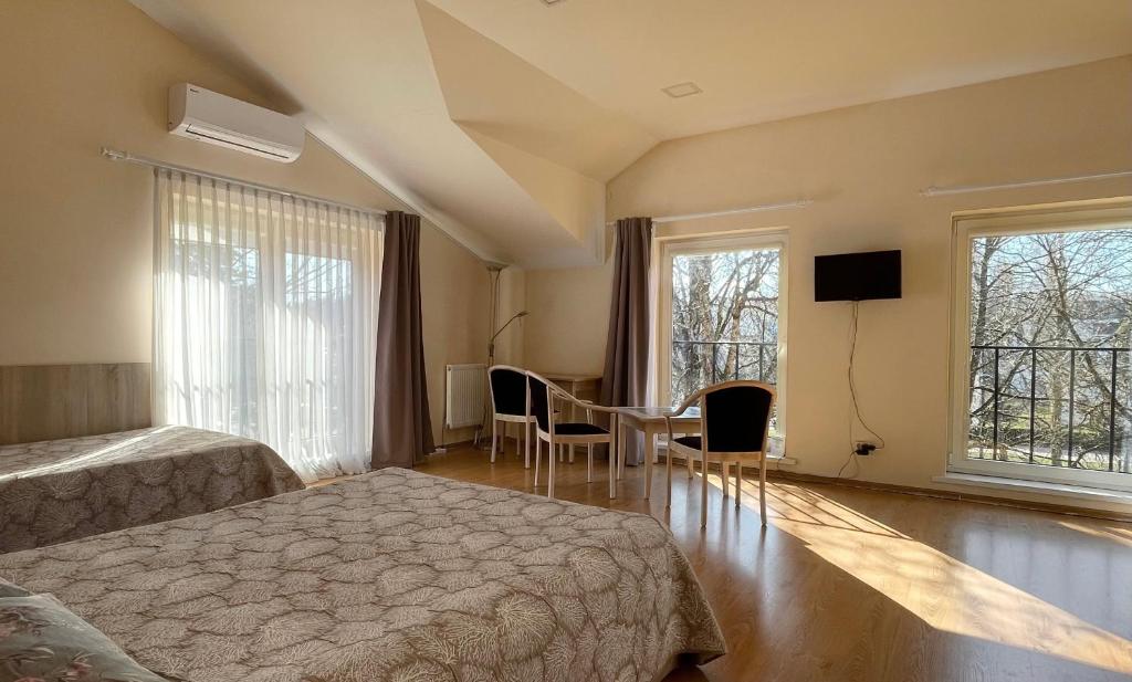 1 dormitorio con 2 camas, mesa y 2 ventanas en Parko Studija, en Birštonas