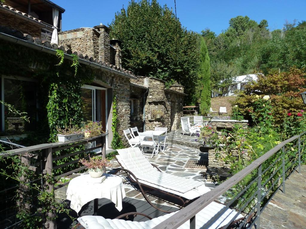 une terrasse avec des chaises et des tables blanches sur une maison dans l'établissement Les Gîtes De La Bastidette, à Saint-Martin-de-Boubaux