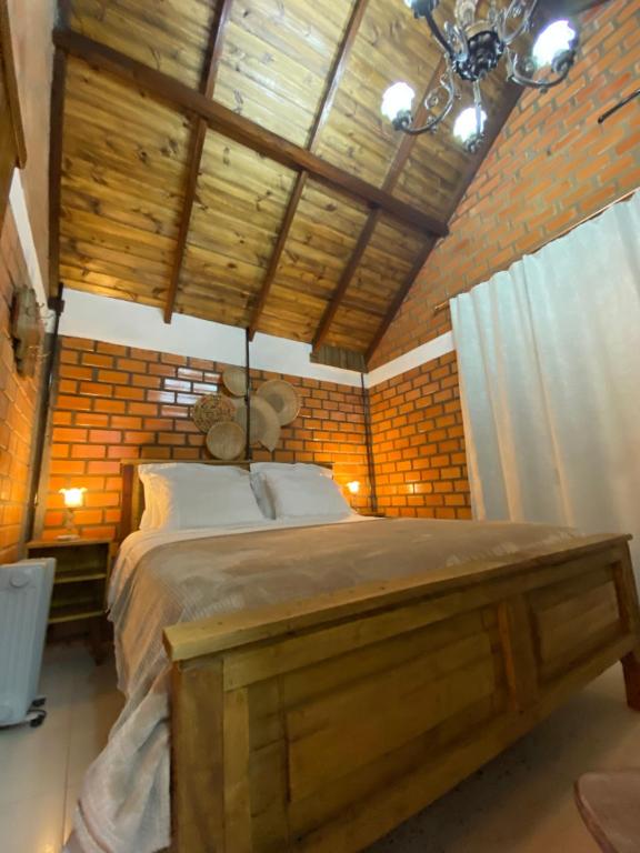 ein Schlafzimmer mit einem großen Bett und einer Holzdecke in der Unterkunft Cabana na Fazenda in São Francisco de Paula