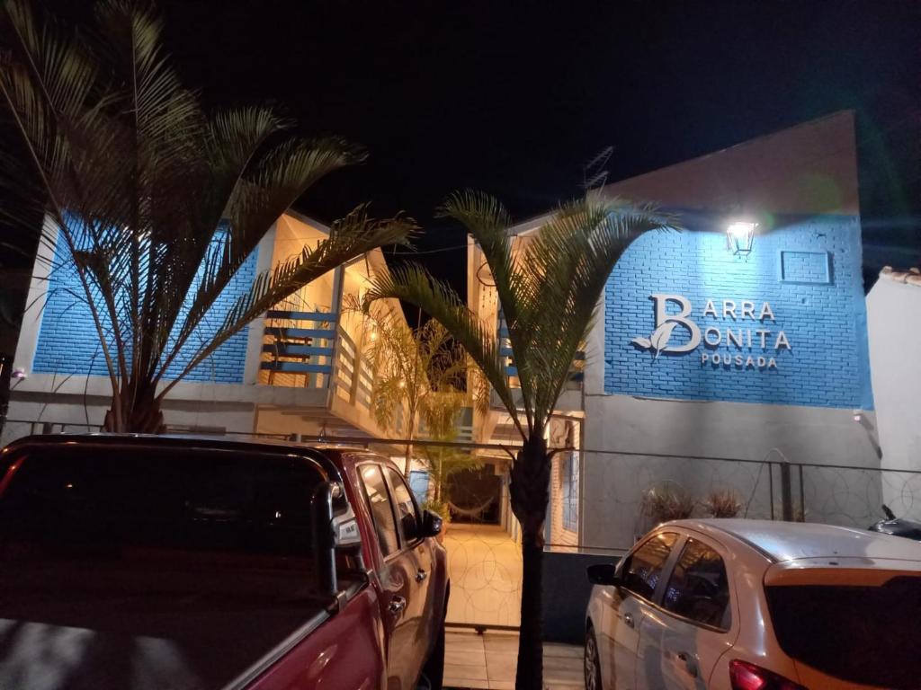 deux voitures garées devant un immeuble avec un panneau dans l'établissement Pousada Barra Bonita, à Bonito