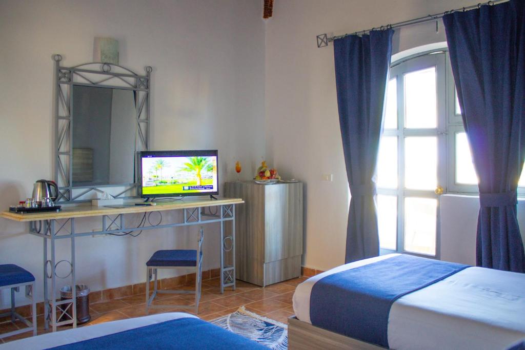sypialnia z 2 łóżkami i biurkiem z telewizorem w obiekcie Protels Beach Club & SPA w Marsa Alam