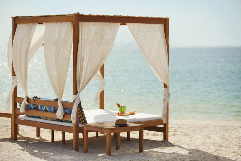 Protels Beach Club & SPA في مرسى علم: سرير على شاطئ مع المحيط في الخلفية