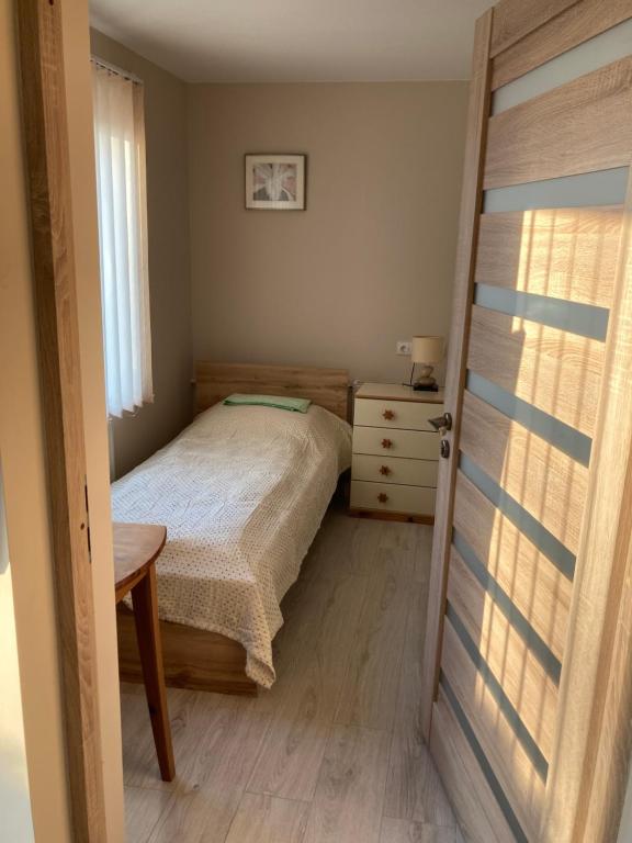 a bedroom with a bed and a table and a window at Nakvynė Biržuose “Širvėnos namai” in Biržai