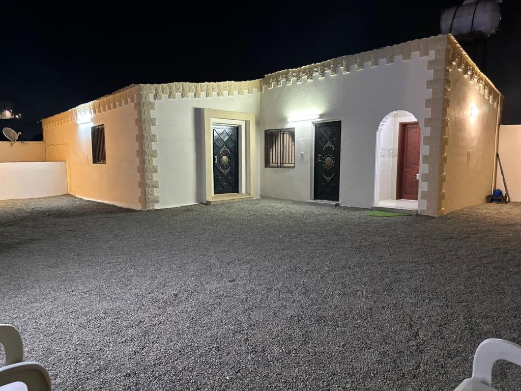 a white building with two doors at night at Old Town House 4 in Ḑubā