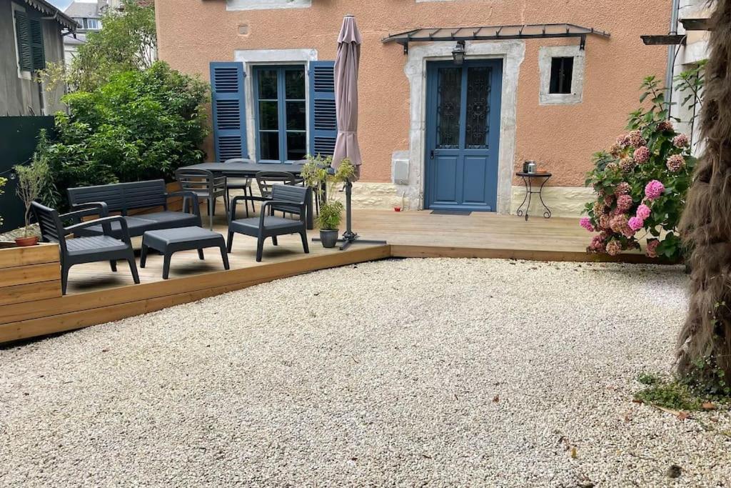 a patio with chairs and a table and an umbrella at Maison et appartement attenant pour 10 personnes avec terrasse, cour et parking in Pau
