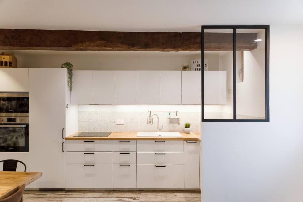 a kitchen with white cabinets and a sink at Maison et appartement attenant pour 10 personnes avec terrasse, cour et parking in Pau