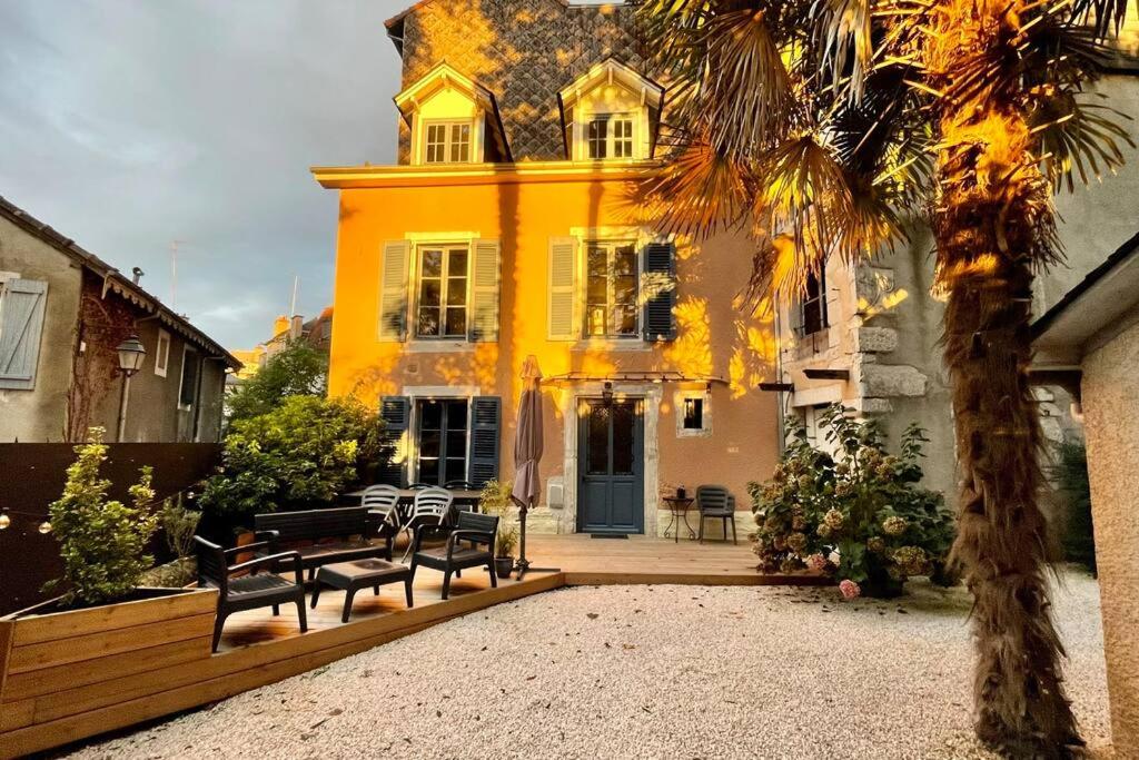 a yellow house with benches in front of it at Maison et appartement attenant pour 10 personnes avec terrasse, cour et parking in Pau