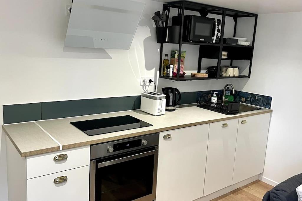 a kitchen with white cabinets and a stove top oven at Maison et appartement attenant pour 10 personnes avec terrasse, cour et parking in Pau