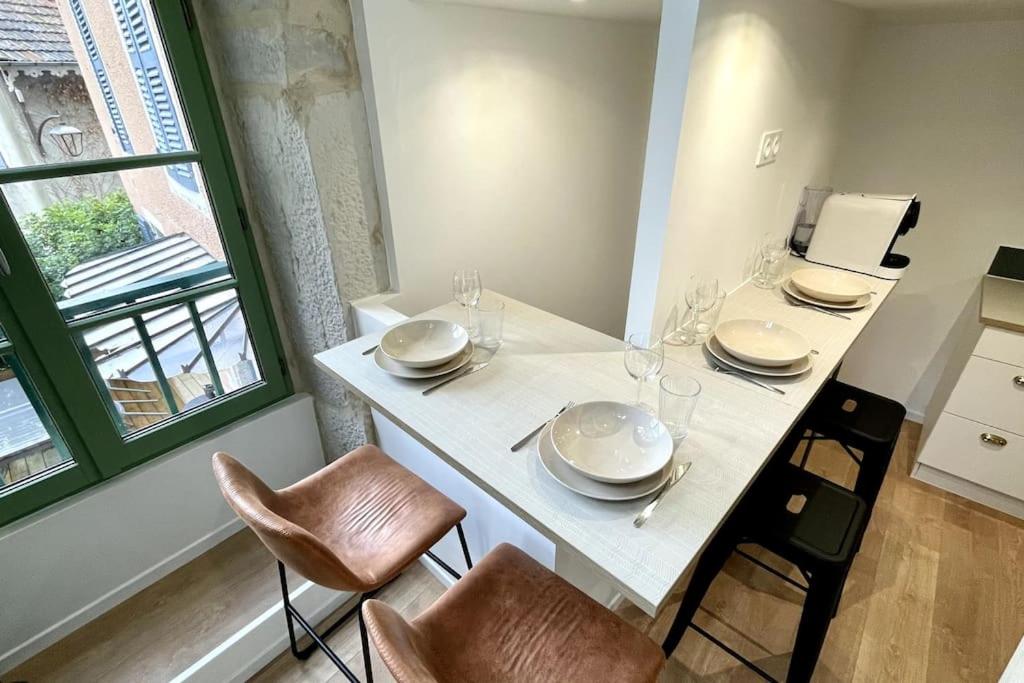 a white table with chairs and plates and wine glasses at Maison et appartement attenant pour 10 personnes avec terrasse, cour et parking in Pau