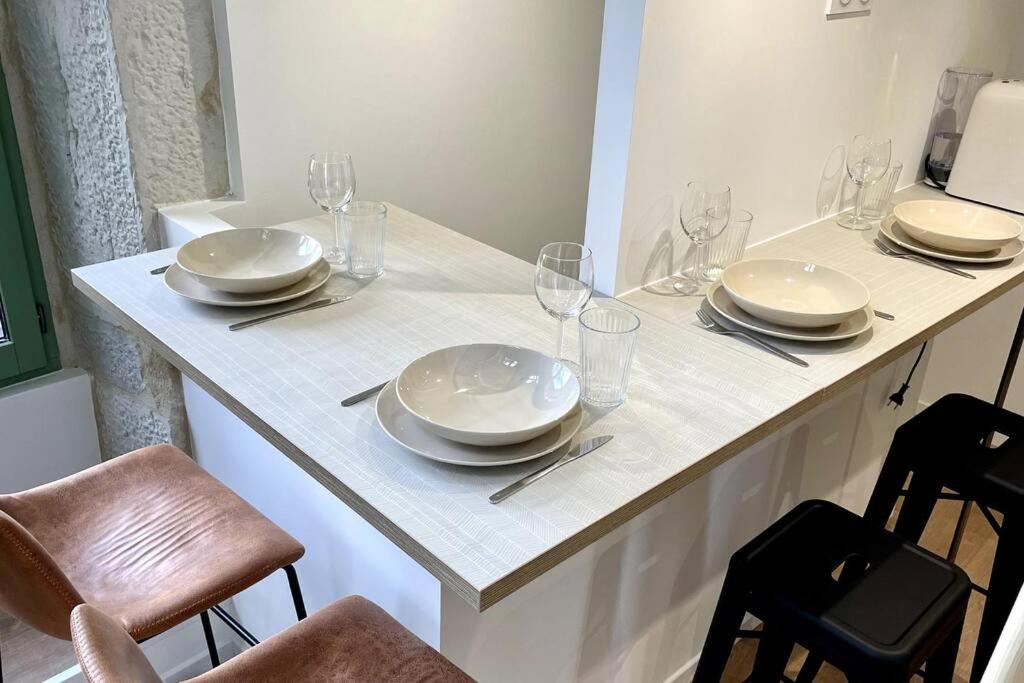 a white table with plates and wine glasses on it at Maison et appartement attenant pour 10 personnes avec terrasse, cour et parking in Pau