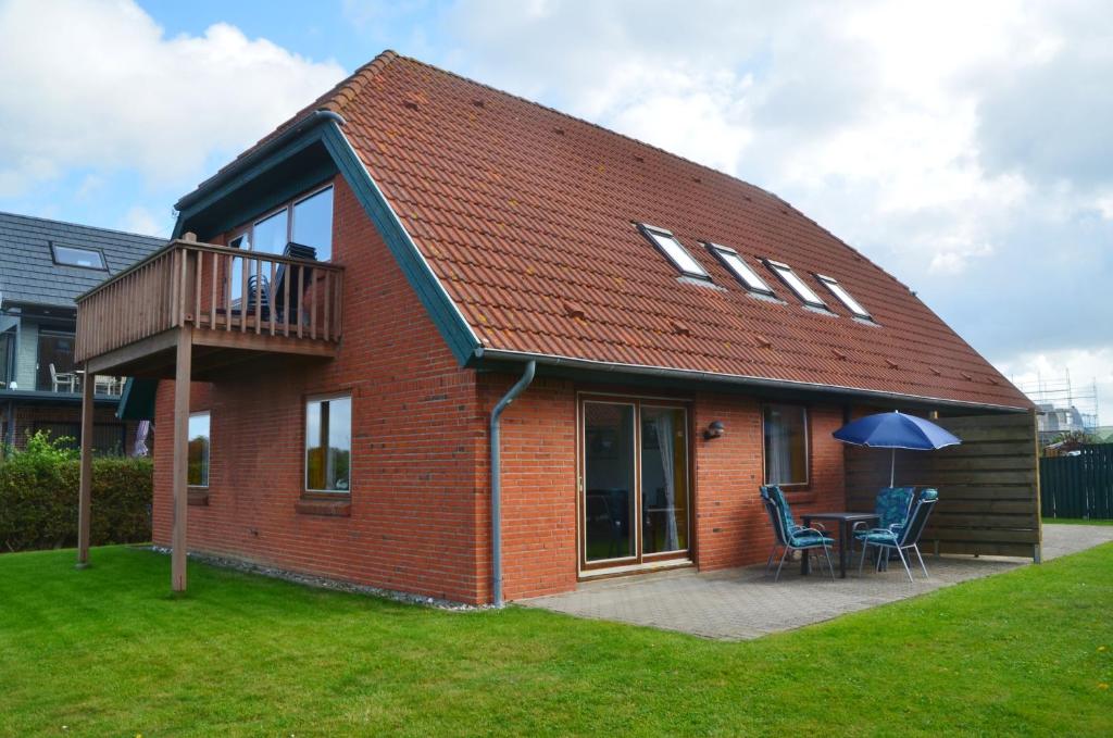 a red brick house with a deck and a table and chairs at Ferienwohnung in Lemkenhafen auf Fehmarn in Fehmarn