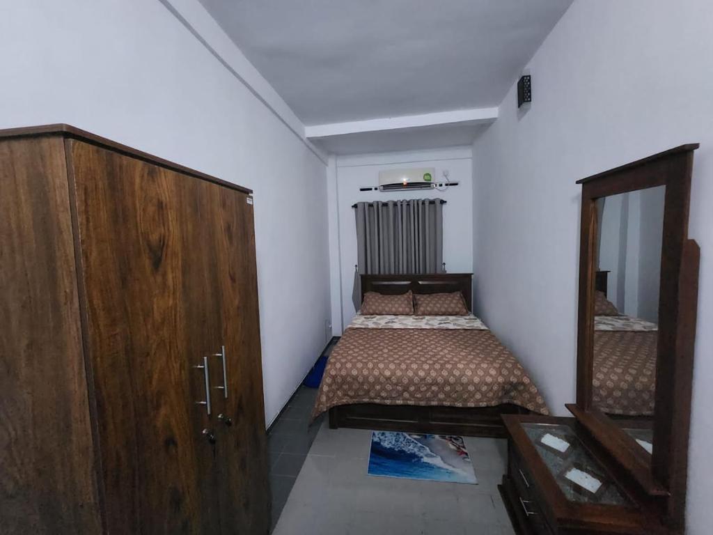 a small bedroom with two beds and a mirror at Andrews residence in Katunayake