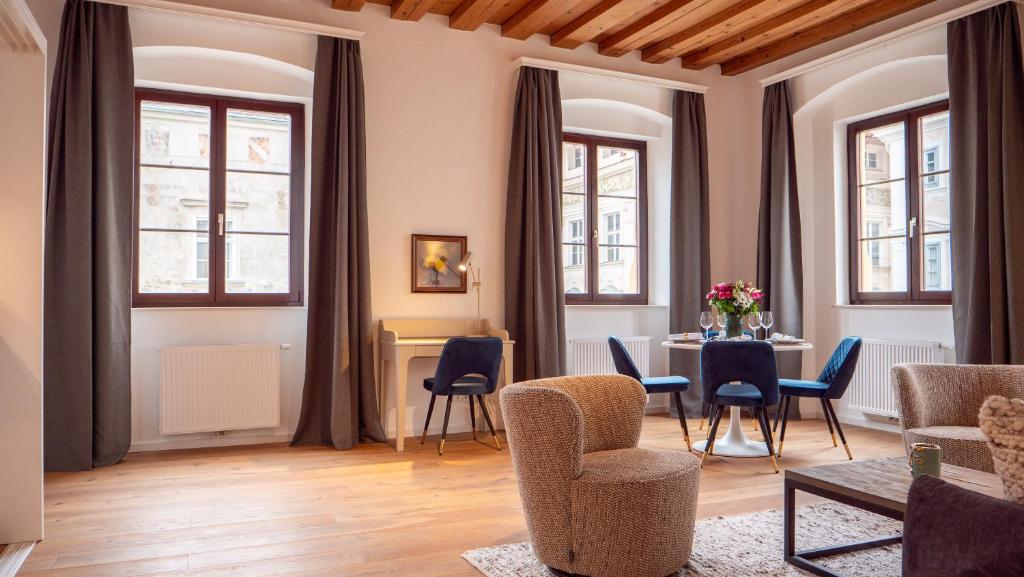 een woonkamer met een tafel, stoelen en ramen bij Smile Apartments im Stadtzentrum in Krems an der Donau