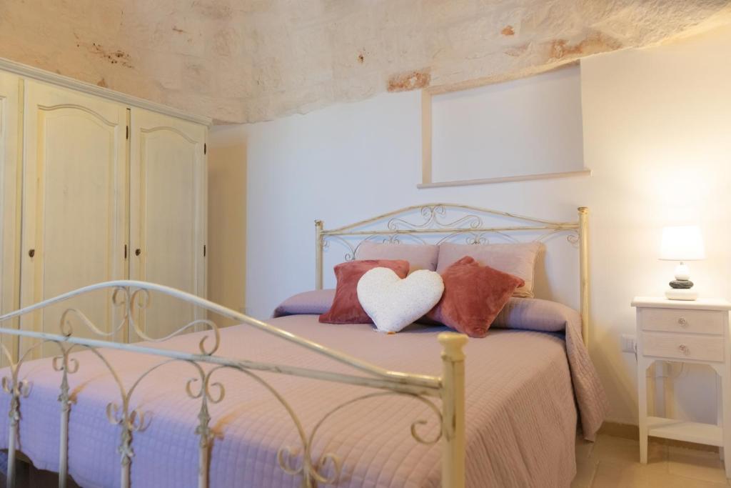 um quarto com uma cama com duas almofadas e uma almofada de coração em Masseria Carperi in the heart of Valle d'Itria em Cisternino