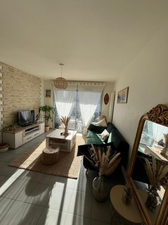 uma sala de estar com um sofá verde e um espelho em Appartement T2 cosy et calme em Baiona