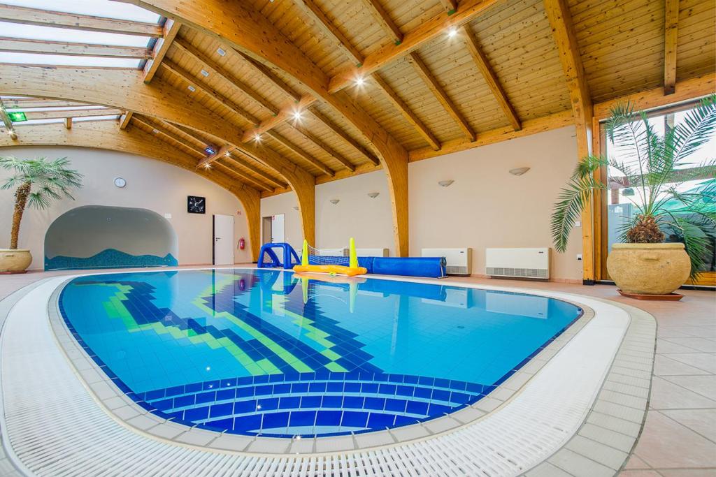 ein großer Pool mit blauen Fliesen in einem großen Zimmer in der Unterkunft Partyház Gödöllő in Gödöllő