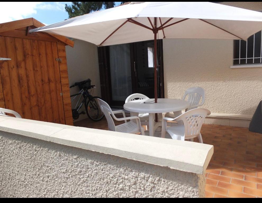 un tavolo bianco e sedie sotto un ombrellone di Appartement Classé 1 * au calme, 300m de l'océan a Soulac-sur-Mer