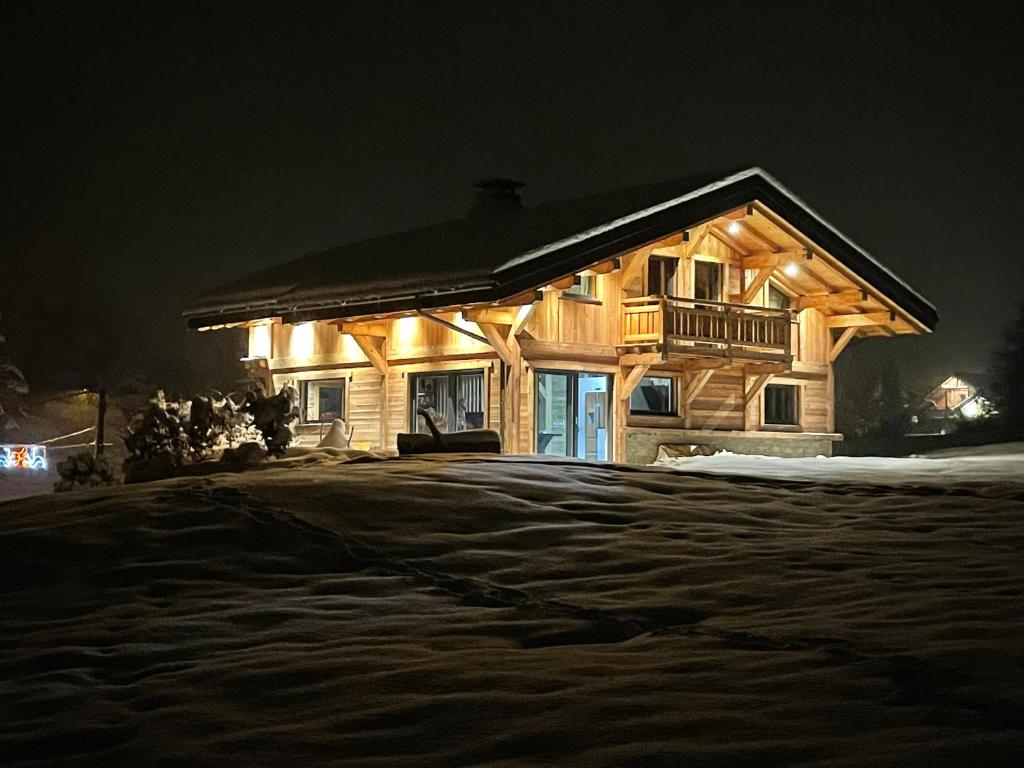 una cabaña de madera por la noche con luces encendidas en Le Chalet de Bequi, en Bellefontaine