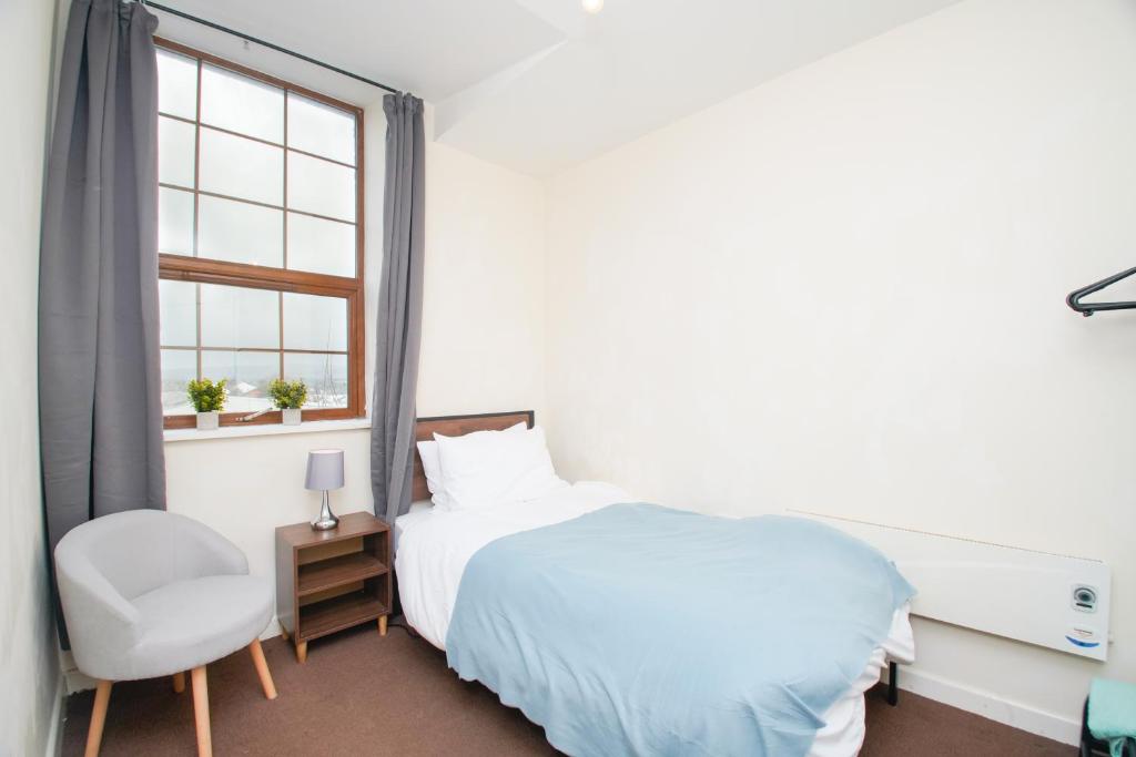 a bedroom with a bed and a chair and a window at 3 bed apartment, centre of Rochdale in Rochdale