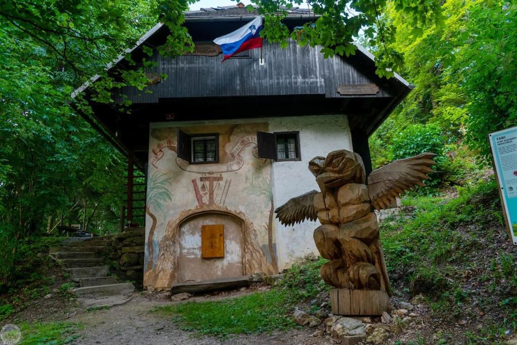 ein kleines Haus mit einer Statue davor in der Unterkunft Home Puščava in Kranj