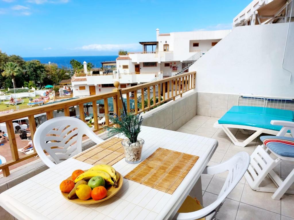 una mesa con un bol de fruta en el balcón en FIRST LINE Los Geranios Ocean View Apartment Air Conditioned 50 m from La Pinta beach en Adeje
