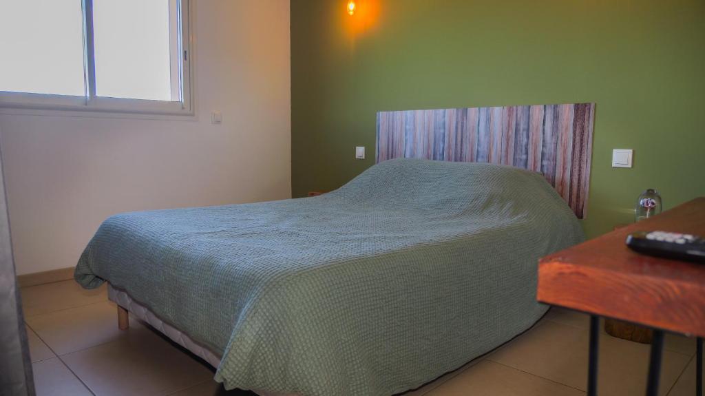 ein kleines Schlafzimmer mit einem Bett und einem Tisch in der Unterkunft ISULA PETRA in Porto-Vecchio