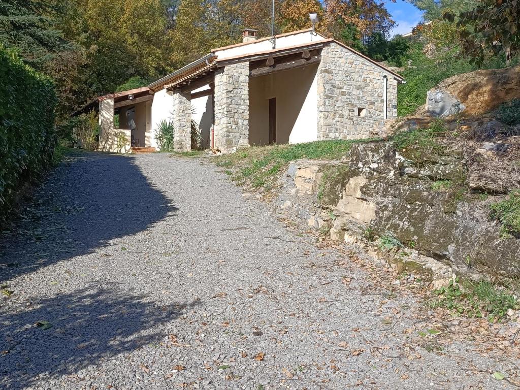 un camino de grava junto a un edificio de piedra en Gîte Au pied du grand cèdre, en Vesseaux