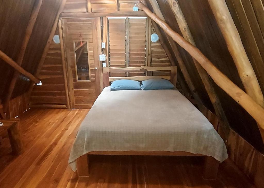 Cama pequeña en habitación con paredes de madera en Treehouse Chilo at Hacienda Nosara en Playa Pelada