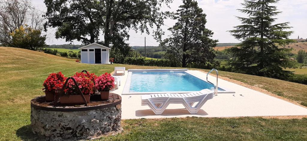 een zwembad met een bank en bloemen in een tuin bij Gîte - Le Moussat in Lagraulet-du-Gers