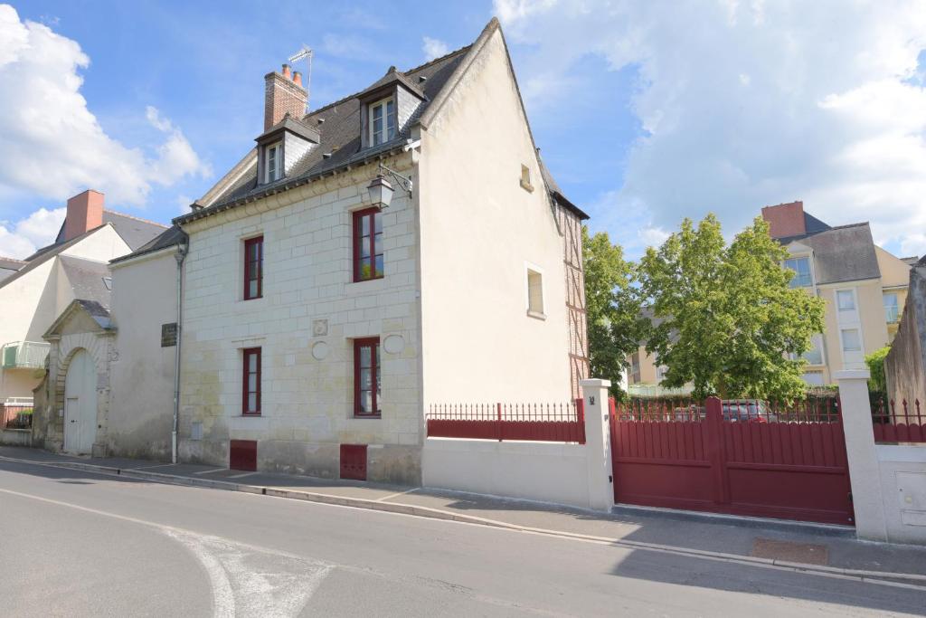 un edificio blanco con una valla roja en una calle en la maison du philosophe, en Amboise