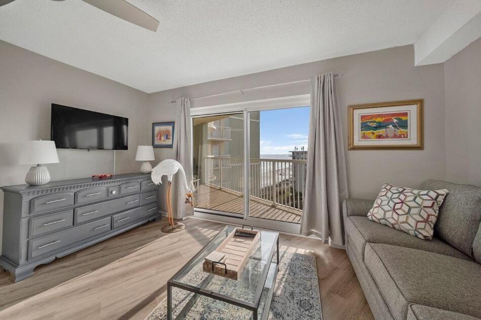 uma sala de estar com um sofá, uma televisão e uma varanda em Tradewinds 806 condo em Orange Beach