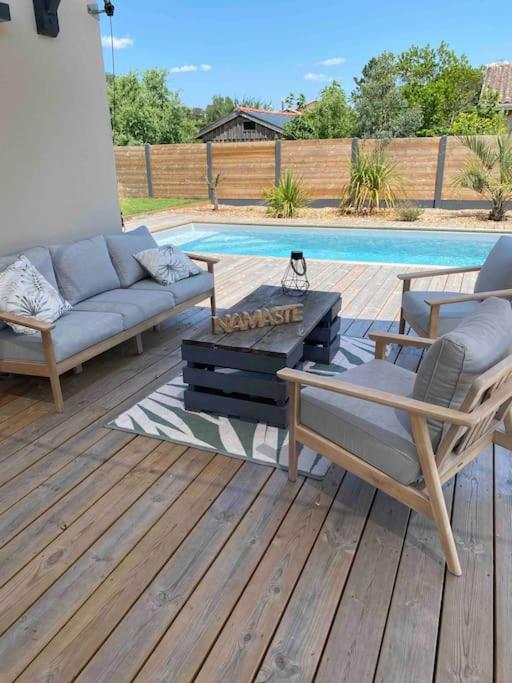d'une terrasse avec un canapé et des chaises à côté de la piscine. dans l'établissement Villa entre Océan et Bassin, piscine chauffée, à Lège-Cap-Ferret