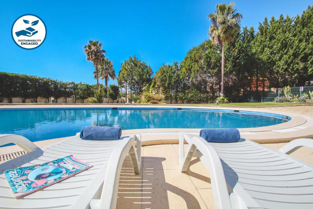a swimming pool with two white lounge chairs next to it at Apartment Rhodes by Algarve Vacation in Albufeira