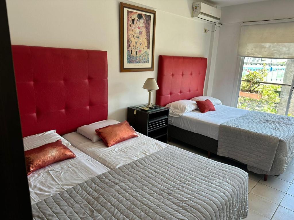 two beds with red headboards in a bedroom at alquilo x dia avenida Corrientes a pasos del Movistar Arena hasta 5 Personas SOLICITAMOS SEÑA in Buenos Aires